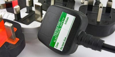 A selection of UK electric plugs; one with a PAT testing label on